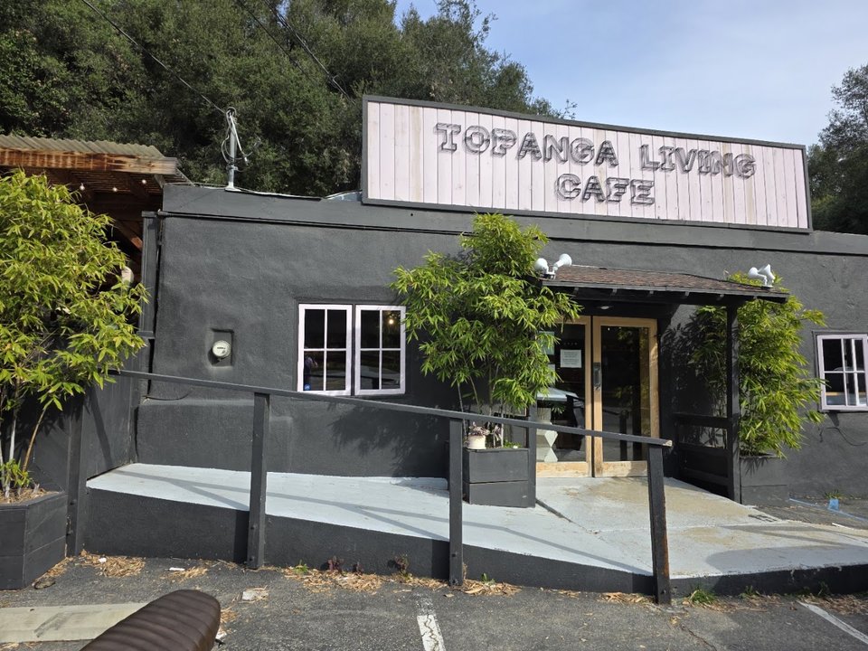 Cafe entrance with outdoor seating and sunlight.